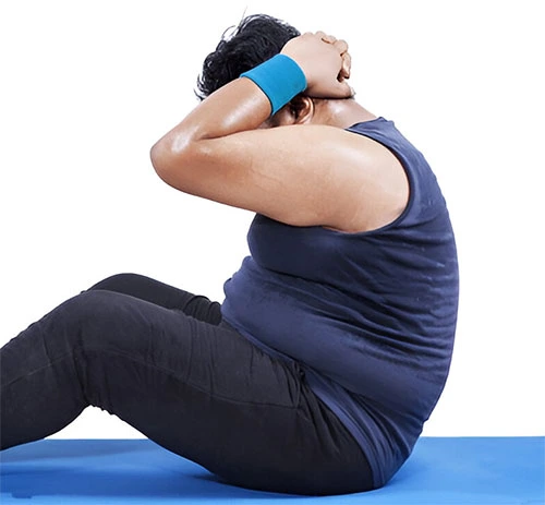 A person performing sit-ups on a fitness mat, promoting physical activity as a key strategy for preventing and managing obesity.