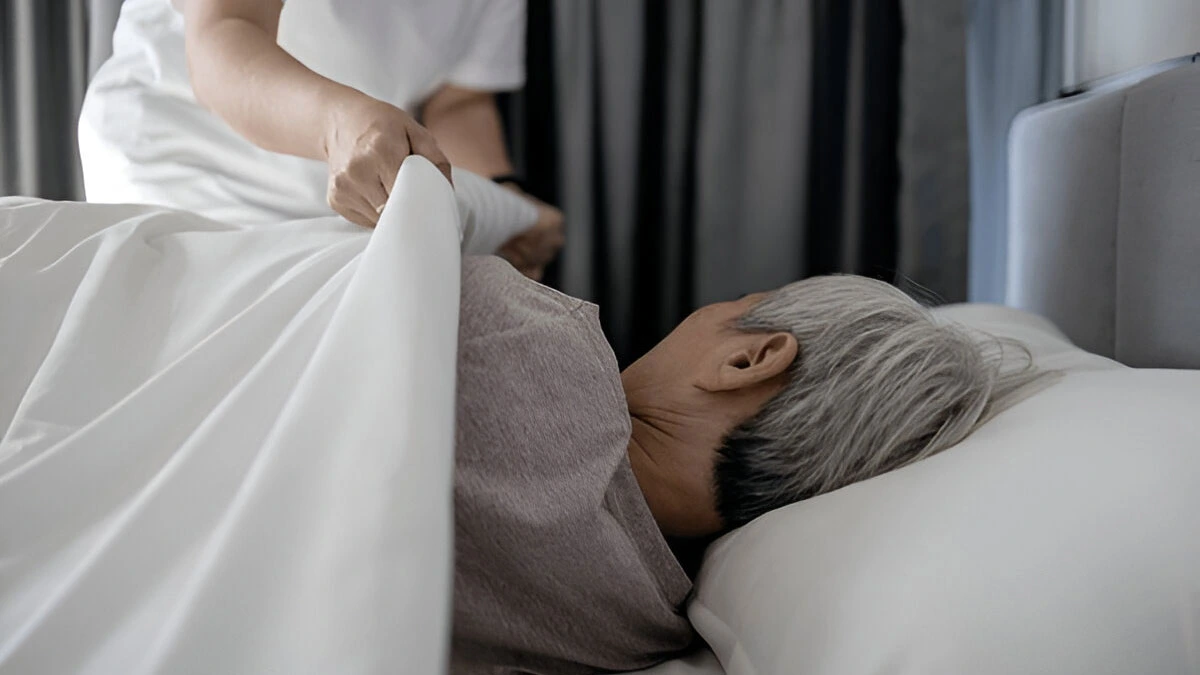 A person lying in bed covering their head with a pillow, expressing how sleep aids in medical recovery